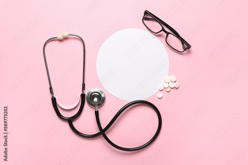 Fototapeta premium Medical stethoscope, prescription pills, and eyeglasses with blank paper circle on pink background