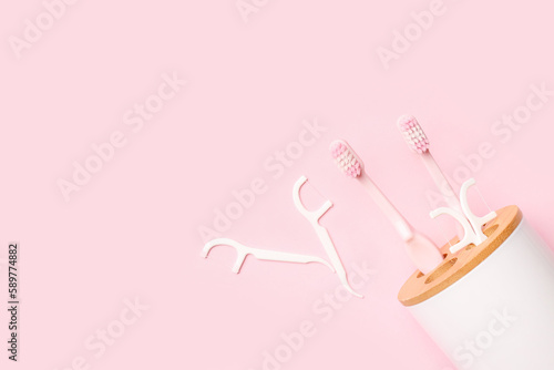 Overturned toothbrush holder and floss toothpicks on pink background