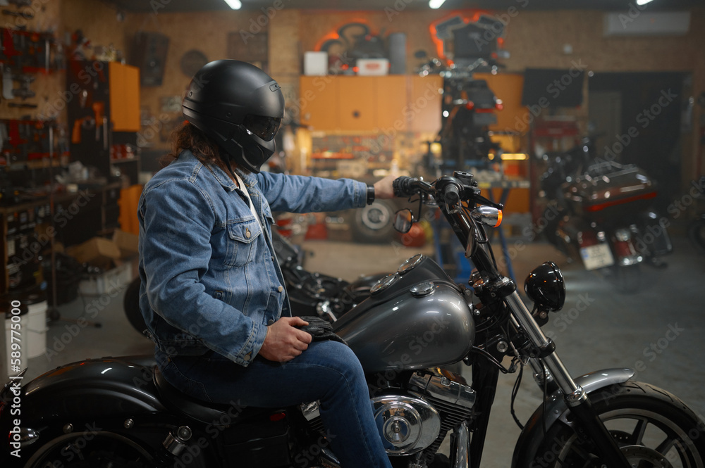 Biker in protective helmet sitting on motorcycle testing new vehicle Biker in protective helmet sitting on motorcycle testing new vehicle