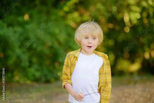 Portrait of cheerful smiling preschooler child during summer holidays on sunny day. Concept of freedom, happy childhood and limitless possibilities.