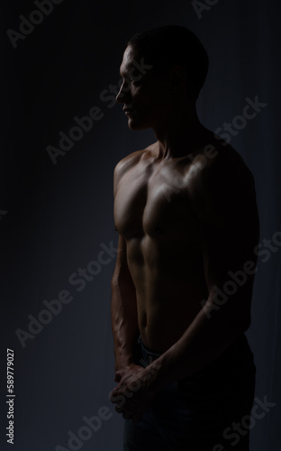 muscular silhouette black background. athletic young man. Black and white dark contrast photo of fitness muscular arms and chest. strong athletic man.