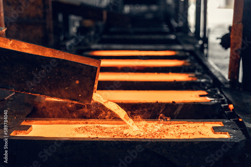 red-hot brass melt pours into the mold in a foundry