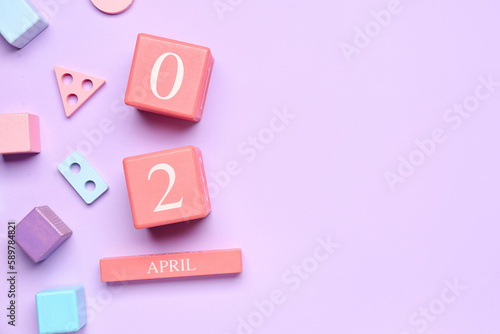 Date of World Autism Awareness Day with baby toys on lilac background