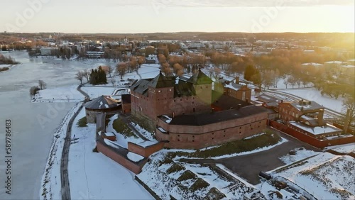 Aerial view away from the Tavastia castle, winter sunset in Hameenlinna, Finland - pull back, drone shot photo