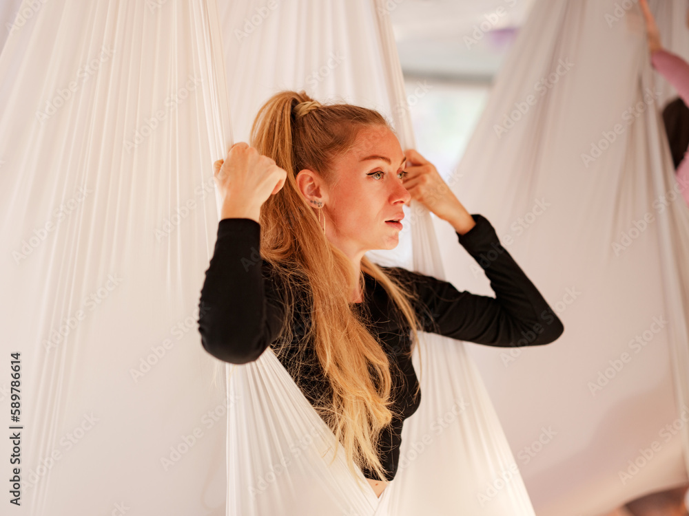 Naklejka premium workshop of air yoga and stretching in yoga studio. women practices different inversion antigravity yoga with hammock. balance between mental and physical, one person effort and achievement concept
