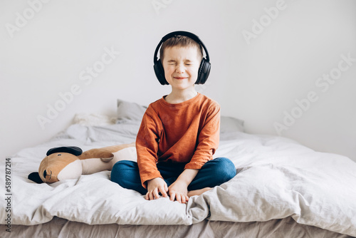 Happy smiling child enjoys listen to the music in headphones at home
