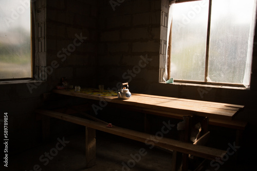 Kettle and food on a wooden table in an unfinished building