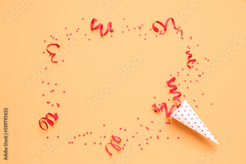 Frame made of party cone with serpentine and confetti on orange background