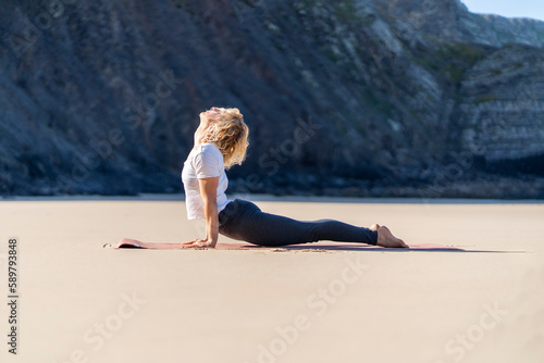 Woman practicing yoga outdoor. Yogi girl practice cobra asana at the beach. Female happiness concept photo