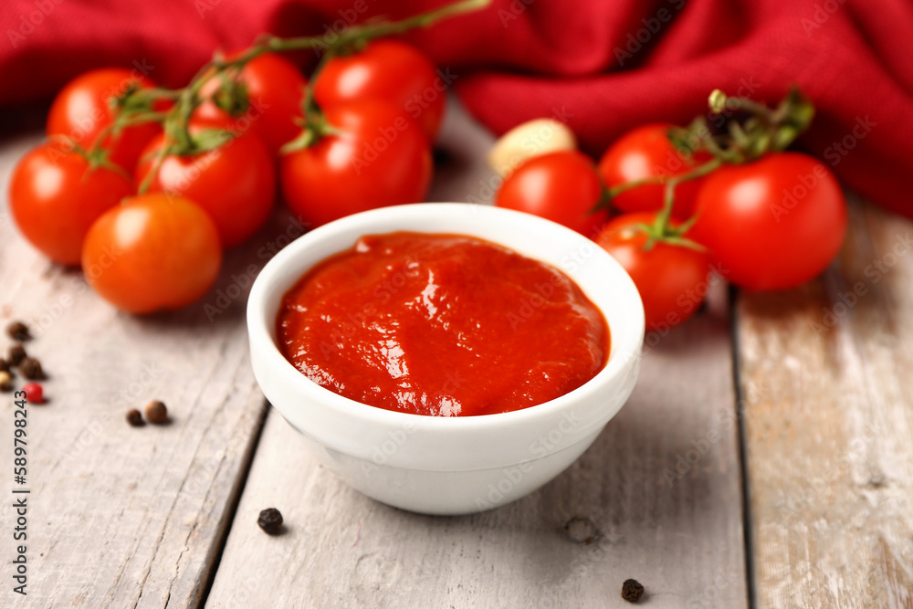 Bowl with tasty tomato paste on light wooden background Bowl with tasty tomato paste on light wooden background