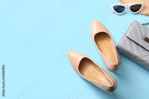 Stylish high heeled shoes and accessories on light blue background