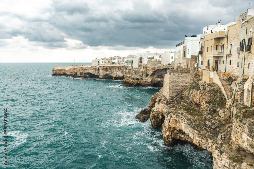Polignano a Mare, Bari, Italy. Old town built on the rocky cliffs. Traveling concept background with old traditional houses, dramatic cloudy sky and beautiful view of Mediterranean Sea