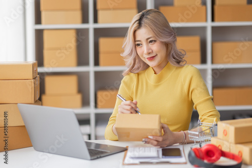 Portrait of Asian young woman SME working with a box at home the workplace.start-up small business owner, small business entrepreneur SME or freelance business online and delivery concept. 