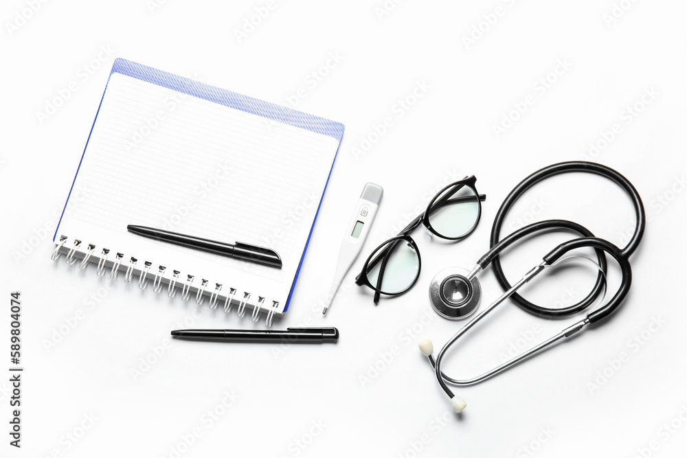 Notebook, stethoscope, glasses and thermometer on white background Notebook, stethoscope, glasses and thermometer on white background