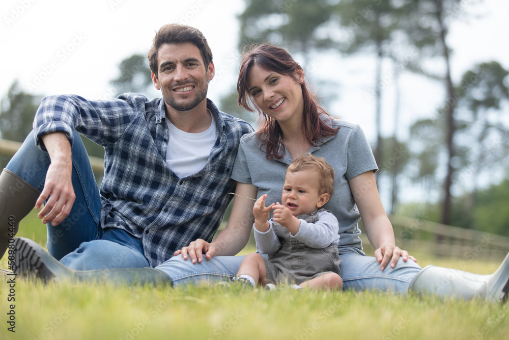 happy beautiful young family sitting on the green grass happy beautiful young family sitting on the green grass