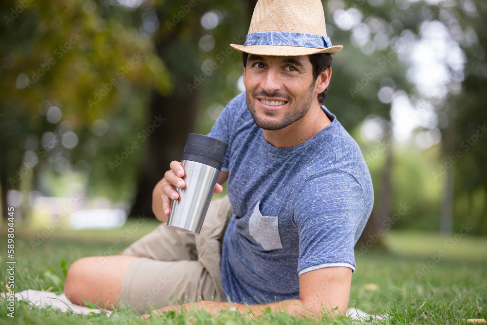handsome young man sitting on the grass near office handsome young man sitting on the grass near office