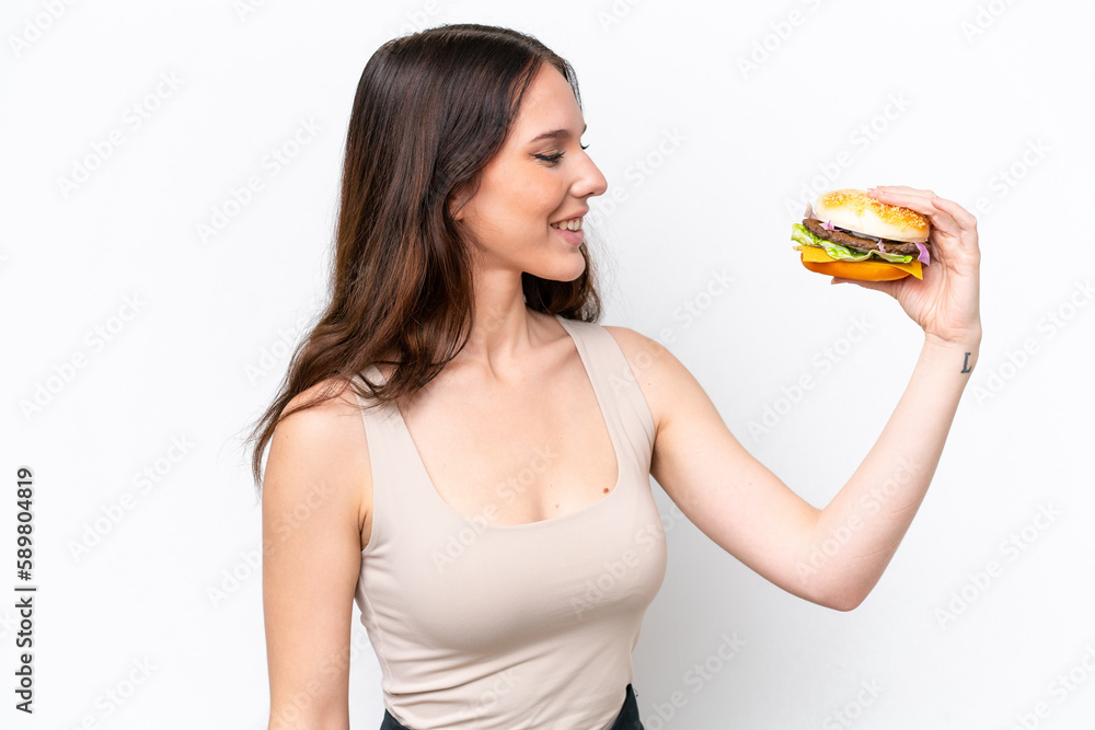 Young caucasian woman holding a burger isolated on white background with happy expression Young caucasian woman holding a burger isolated on white background with happy expression