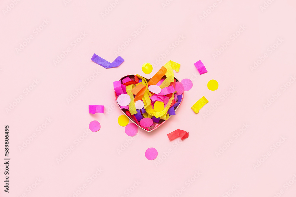 Heart-shaped box with colorful confetti on pink background