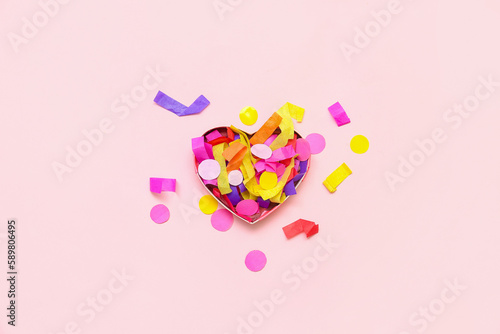 Heart-shaped box with colorful confetti on pink background