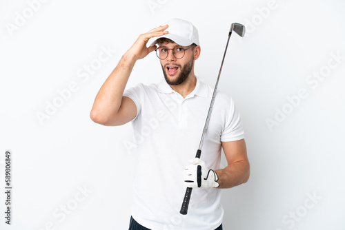 Handsome young man playing golf isolated on white background doing surprise gesture while looking to the side