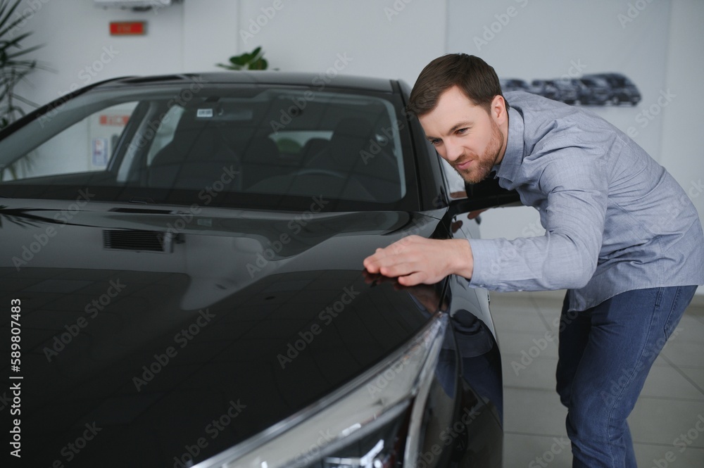 Young man is choosing a new vehicle in car dealership. Young man is choosing a new vehicle in car dealership.