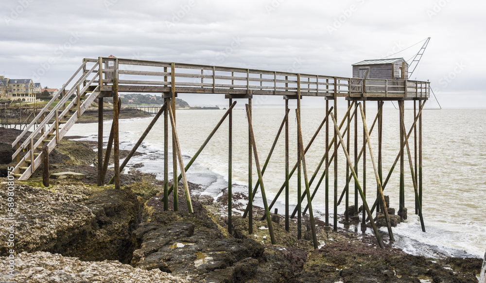 Fisherman's hut made of wood and resting on piles along the Atlantic ocean's coastline during a cloudy day