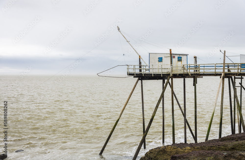 Fisherman's hut made of wood and resting on piles along the Atlantic ocean's coastline during a cloudy day