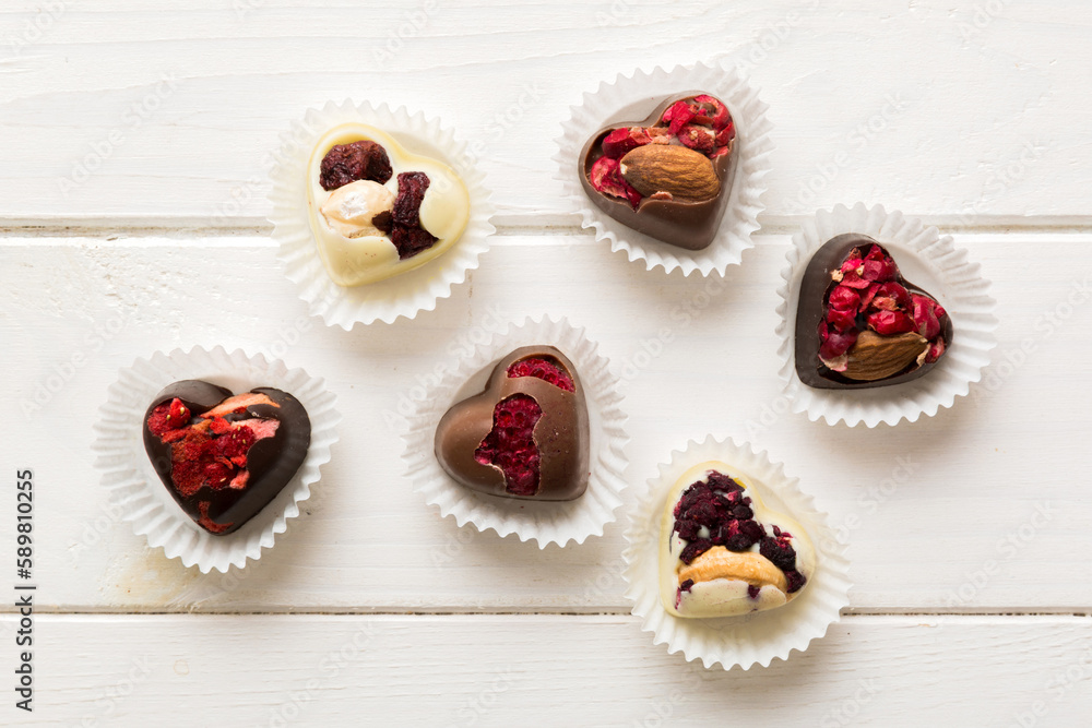 chocolate sweets in the form of a heart with fruits and nuts on a colored background. top view with space for text, holiday concept chocolate sweets in the form of a heart with fruits and nuts on a colored background. top view with space for text, holiday concept
