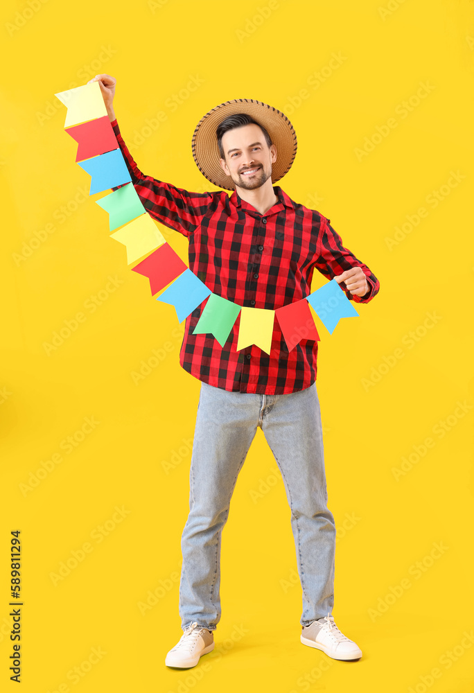 Handsome man with flags on yellow background. Festa Junina (June Festival) celebration Handsome man with flags on yellow background. Festa Junina (June Festival) celebration
