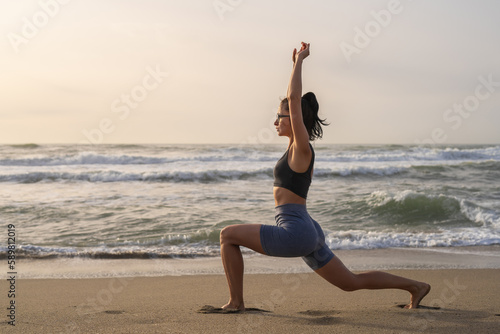 beautiful young girl is engaged in fitness on the seashore at dawn