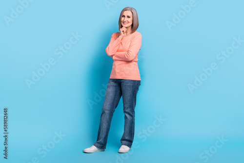 Full size photo of pleasant friendly smart grandmother dressed pink pullover jeans finger on chin isolated on blue color background