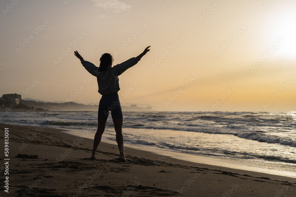 beautiful young girl is engaged in fitness on the seashore at dawn