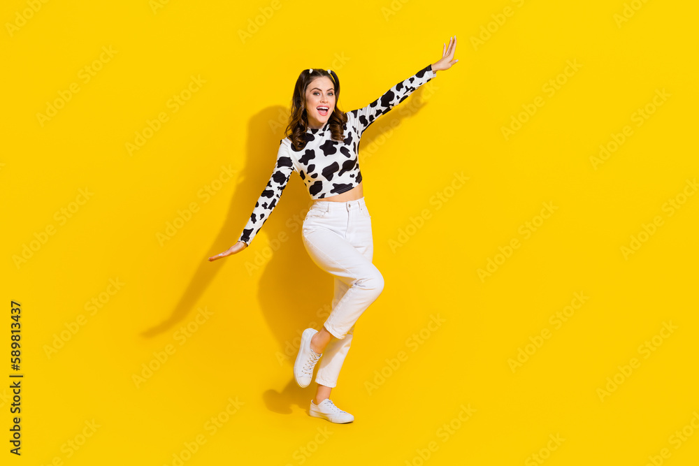 Obraz premium Full length photo of excited pretty girl wear cow skin shirt having fun arms sides empty space isolated yellow color background