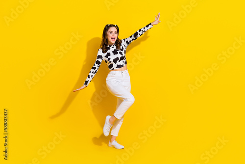 Full length photo of excited pretty girl wear cow skin shirt having fun arms sides empty space isolated yellow color background