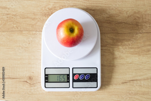 Fresh red apple on white kitchen scales in the kitchen view from above. The concept of proper nutrition and healthy lifestyle