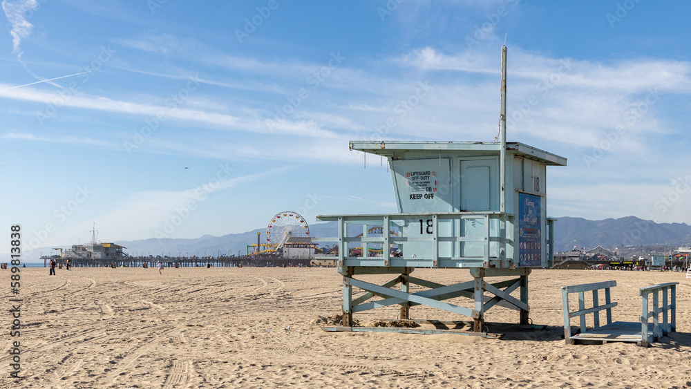 A lifeguard tower on Santa Monica beach with pier in the background located in California USA taken on February 5th 2023