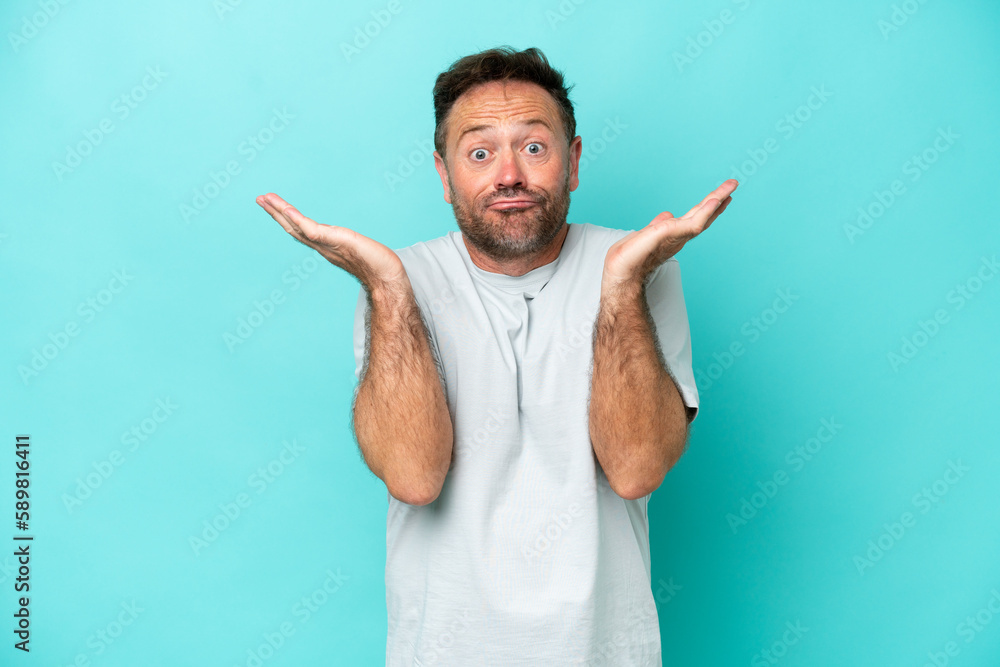 Middle age caucasian man isolated on blue background making doubts gesture Middle age caucasian man isolated on blue background making doubts gesture