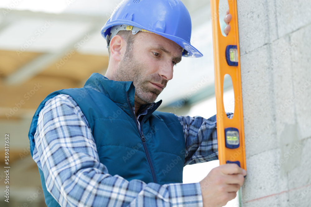 builder holds a professional tool while measuring the wall builder holds a professional tool while measuring the wall
