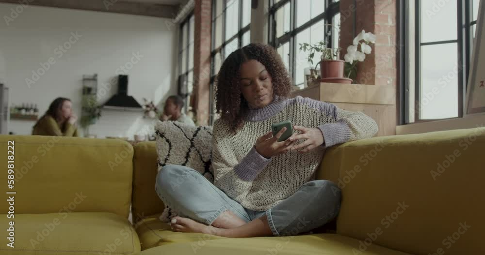 Female Student on Sofa looking at Smart phone in Warehouse conversion Female Student on Sofa looking at Smart phone in Warehouse conversion