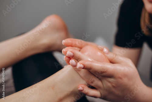 Young woman having feet massage in beauty salon, close up view.