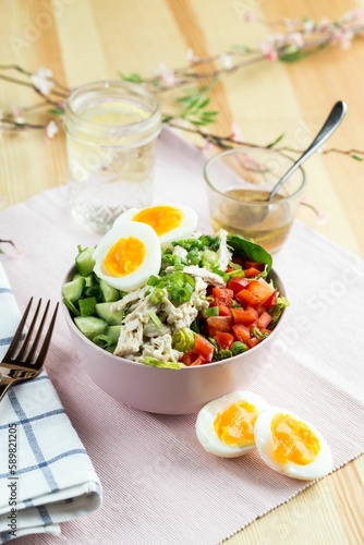Healthy breakfast salad with eggs and fresh vegetables with a cup of tea on the blurred background