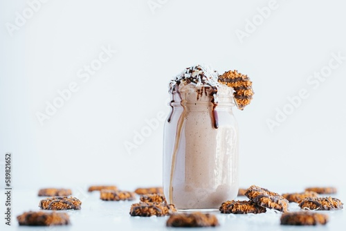 Closeup shot of a delicious cookie shake in a glass jar surrounded by cookies