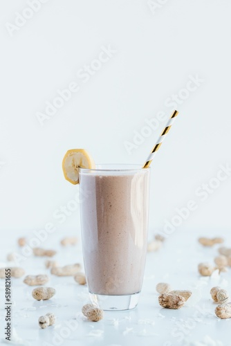Closeup shot of a delicious cookie shake in a tall glass cup surrounded by peanuts