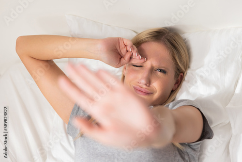 Dissatisfied blond young lady woman hiding her face closing eyes with handssleepy woman doesn't want to get up wake up early in the morning and going at work study.