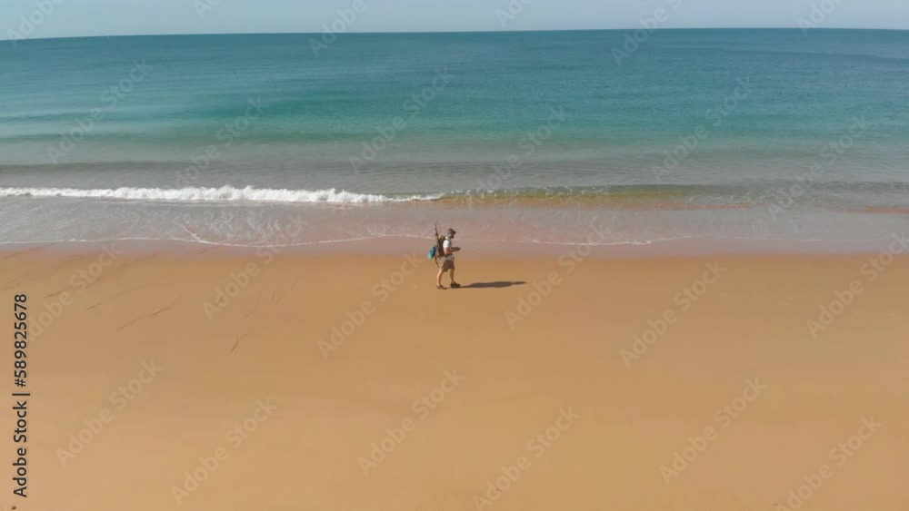 Aerial shot orbiting around a man walking along a calm ocean on a beach in Southern Australia. Aerial shot orbiting around a man walking along a calm ocean on a beach in Southern Australia.