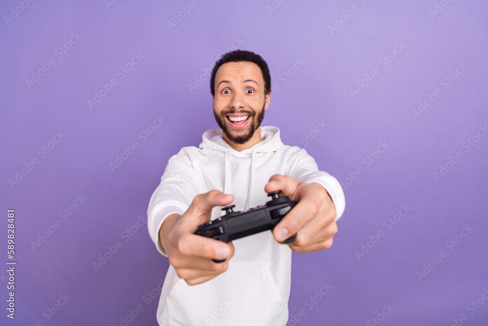 Photo of handsome positive man hold controller playing video games isolated on violet color background Photo of handsome positive man hold controller playing video games isolated on violet color background
