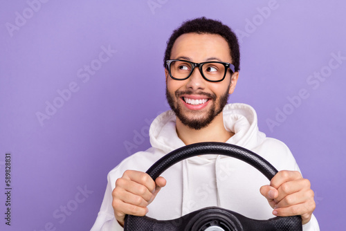Portrait of young happy smile man wear sweatshirt driving steering wheel look empty space new rules isolated on purple color background