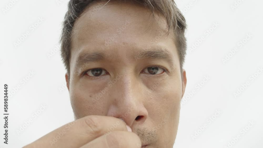Asian man wiping his nostril with tissue paper close up. Cleansing and healthcare concept. Asian man wiping his nostril with tissue paper close up. Cleansing and healthcare concept.