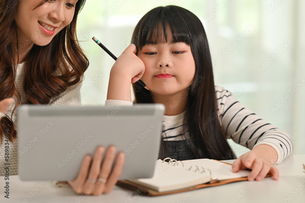 Bored little student girl doing homework with mother at home. Homeschooling and education concept Bored little student girl doing homework with mother at home. Homeschooling and education concept
