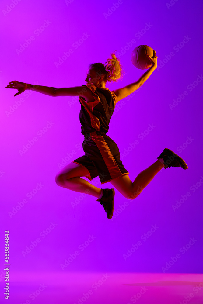 Full-length dynamical image of young female basketball player, girl training with ball against white studio background. Concept of professional sport, hobby, healthy lifestyle, action and motion